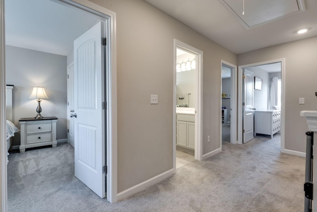 hallway featuring carpet floors, baseboards, a healthy amount of sunlight, and attic access