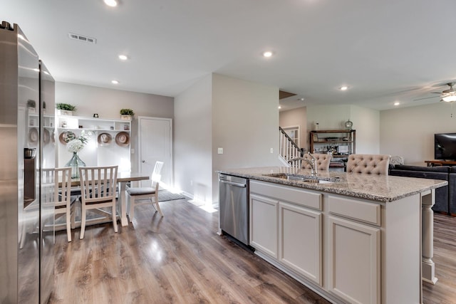 kitchen featuring visible vents, dishwasher, a sink, light wood finished floors, and open floor plan