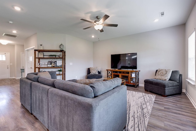 living area with a ceiling fan, baseboards, visible vents, and wood finished floors