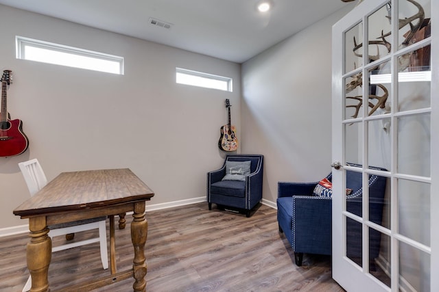 sitting room with baseboards, visible vents, and wood finished floors