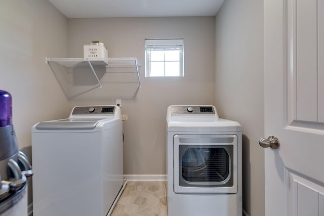 clothes washing area featuring washing machine and clothes dryer, laundry area, and baseboards