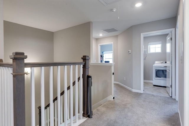 hallway featuring visible vents, baseboards, washer / clothes dryer, carpet flooring, and an upstairs landing