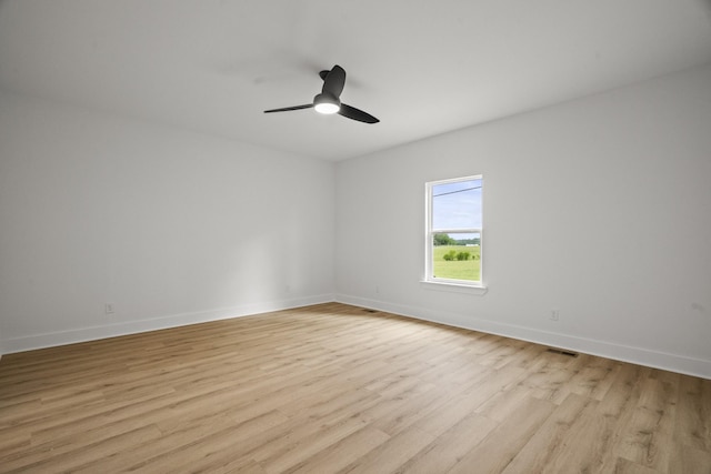 empty room featuring baseboards, ceiling fan, visible vents, and light wood-style flooring