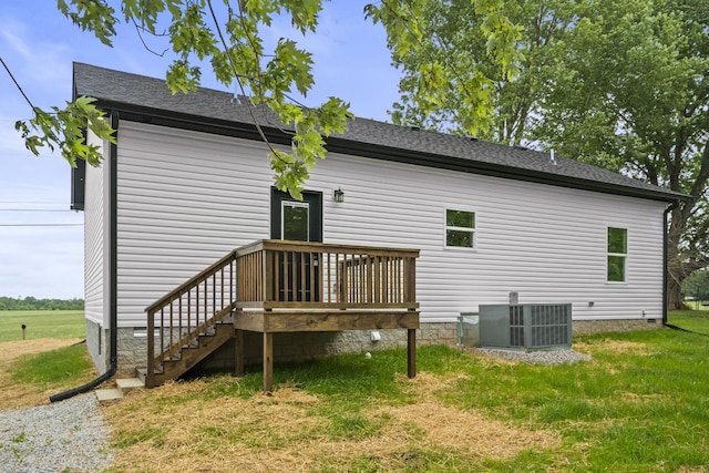 back of house with a shingled roof, central AC, and a yard