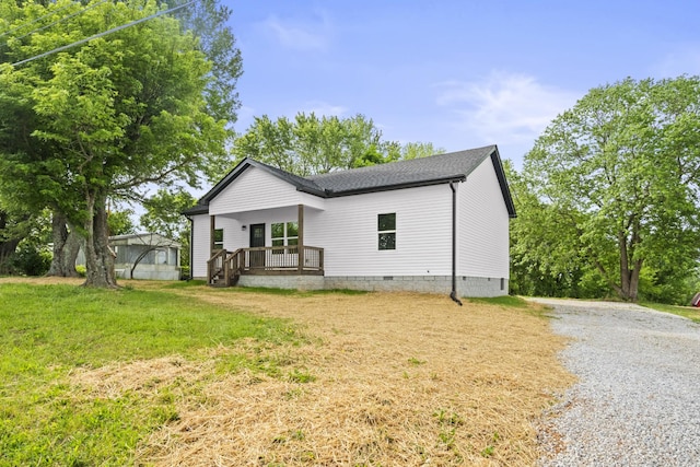 view of front facade with a front lawn, gravel driveway, a shingled roof, crawl space, and a porch