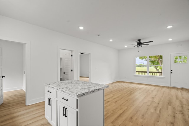 interior space featuring light wood-style floors, a ceiling fan, baseboards, and a kitchen island