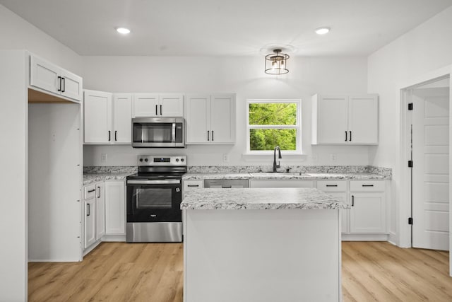 kitchen featuring a sink, appliances with stainless steel finishes, light wood-style floors, and a center island