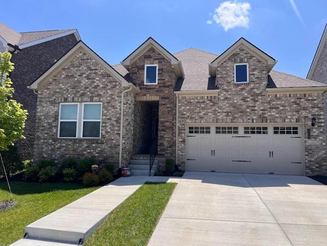 view of front of property with an attached garage, concrete driveway, brick siding, and a front yard