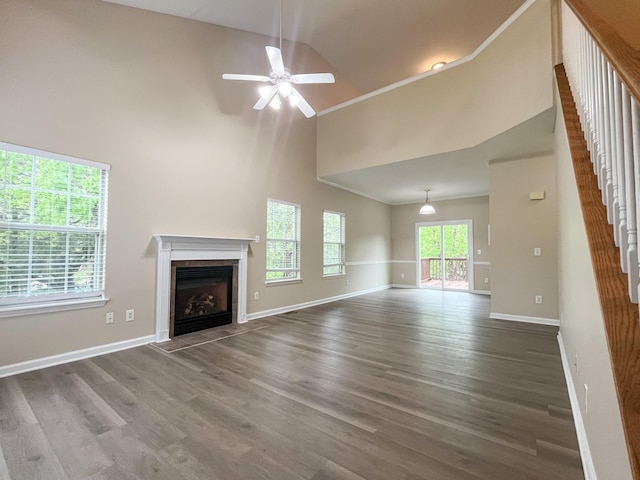 unfurnished living room with a fireplace with flush hearth, stairs, a ceiling fan, and wood finished floors