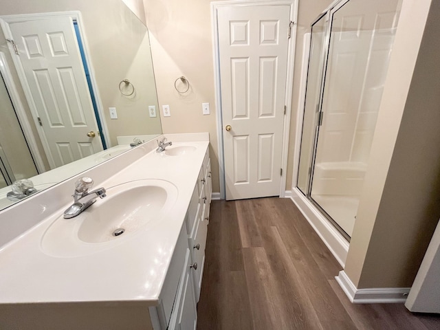 full bath featuring a stall shower, a sink, and wood finished floors