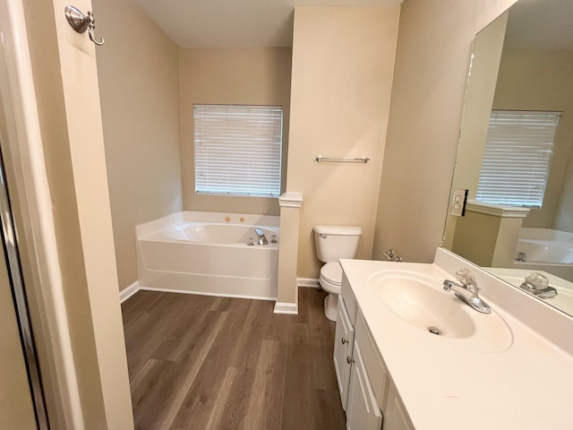 bathroom featuring a garden tub, baseboards, wood finished floors, and toilet