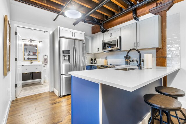 610 21st Ave N Unit 302, Nashville, TN 37203 - kitchen featuring a kitchen bar, light wood-type flooring, light countertops, a peninsula, and stainless steel appliances