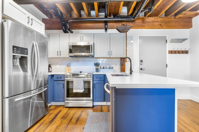 610 21st Ave N Unit 302, Nashville, TN 37203 - kitchen featuring a peninsula, appliances with stainless steel finishes, a sink, and blue cabinets