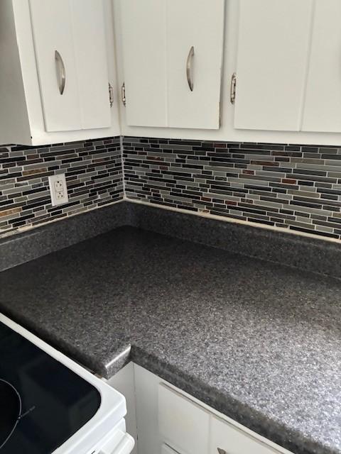 4660 Dover Rd, Indian Mound, TN 37079 - room details with decorative backsplash, range, white cabinets, and dark countertops