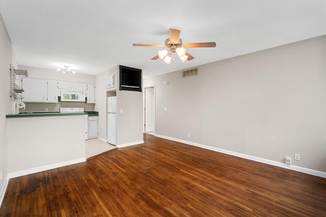 unfurnished living room featuring baseboards, visible vents, wood finished floors, and ceiling fan with notable chandelier