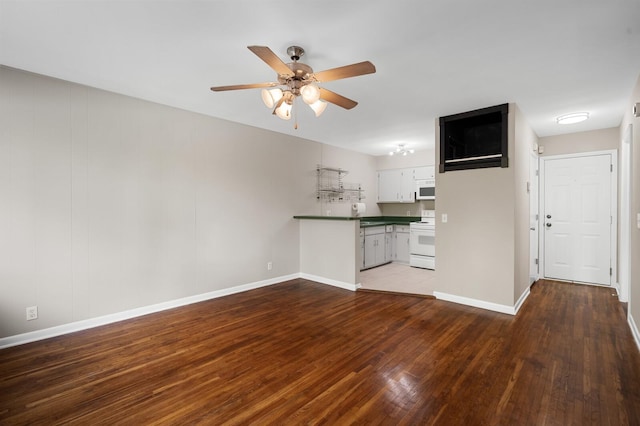 unfurnished living room featuring a ceiling fan, baseboards, and wood finished floors