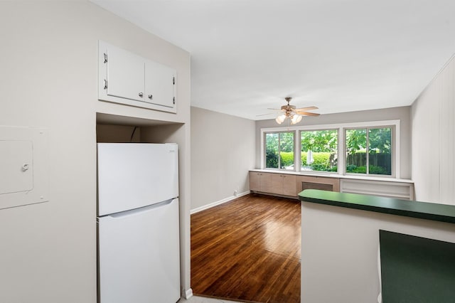 kitchen with freestanding refrigerator, wood finished floors, baseboards, white cabinets, and a ceiling fan