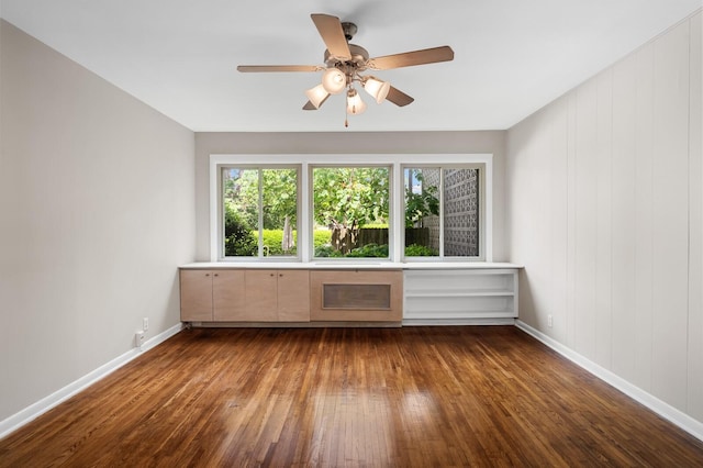 empty room with baseboards, ceiling fan, and dark wood-type flooring