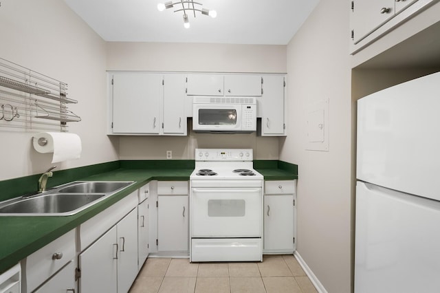 kitchen featuring dark countertops, a sink, light tile patterned floors, white cabinets, and white appliances