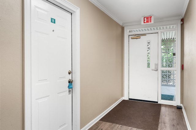doorway with crown molding, baseboards, and wood finished floors