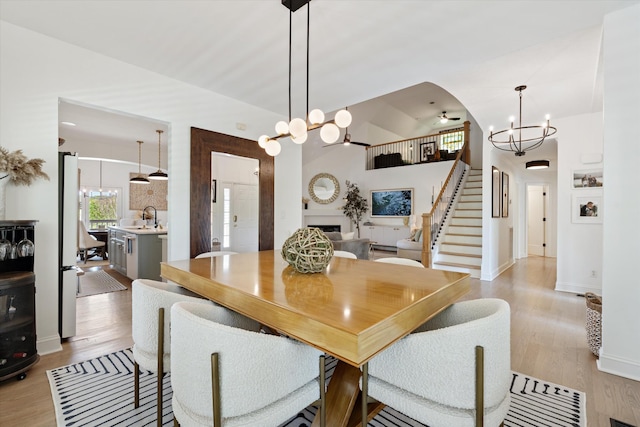 5960 Lickton Pike, Goodlettsville, TN 37072 - dining space featuring a fireplace, light wood-type flooring, high vaulted ceiling, a notable chandelier, and stairs