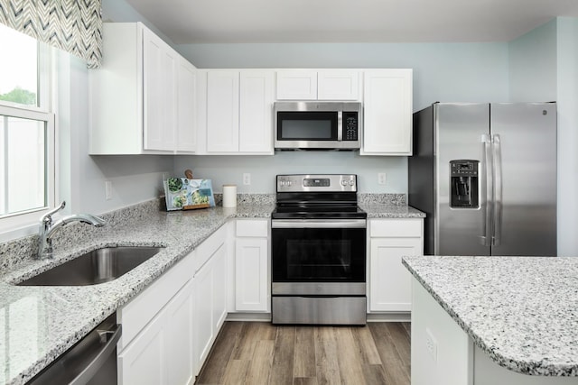 kitchen featuring a sink, appliances with stainless steel finishes, white cabinets, and wood finished floors
