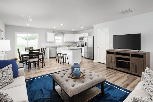 living area with recessed lighting, visible vents, and light wood finished floors