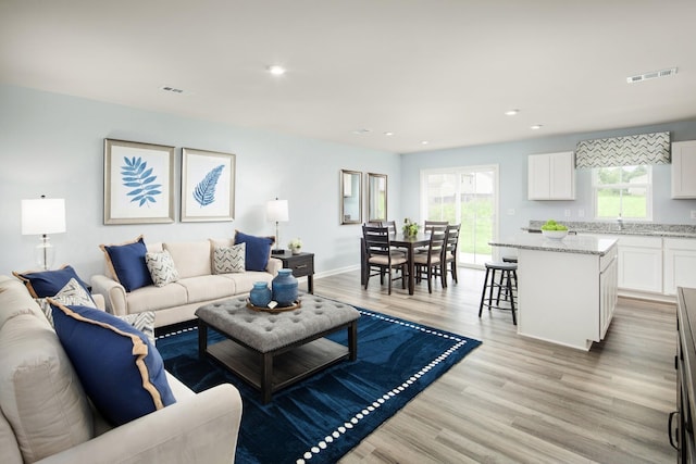 living area with recessed lighting, light wood finished floors, and visible vents