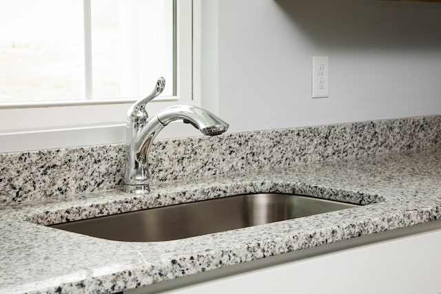 details featuring a sink and light stone counters