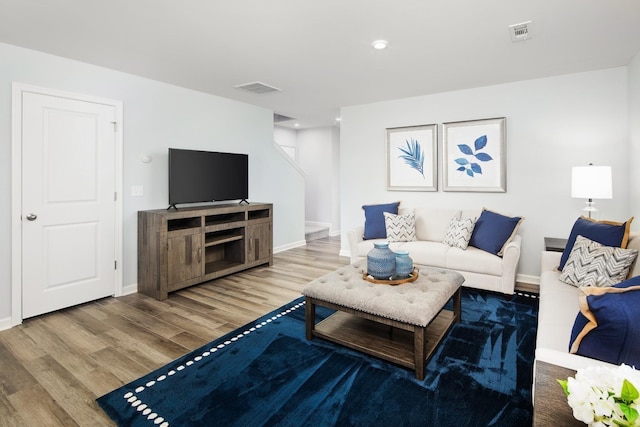 living room featuring visible vents, baseboards, and wood finished floors