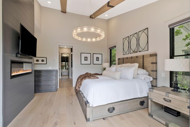 bedroom with a high ceiling, multiple windows, and light wood-style floors