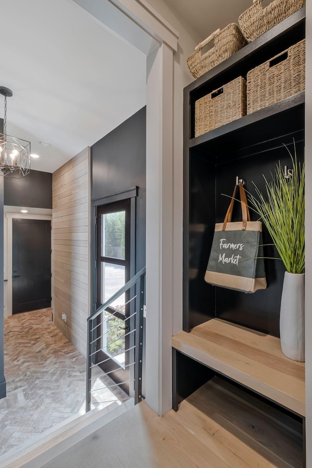 mudroom with wood walls, a notable chandelier, and wood finished floors