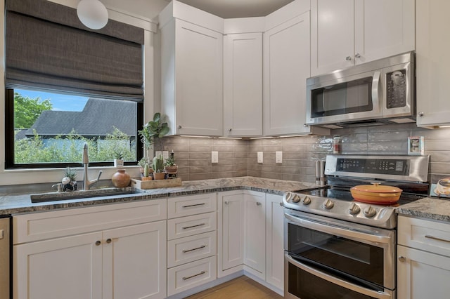 kitchen with a sink, white cabinets, stainless steel appliances, and tasteful backsplash