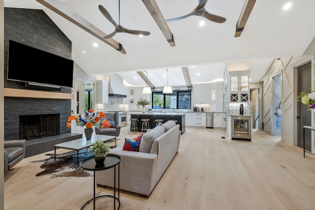 living room with a ceiling fan, light wood-type flooring, and beam ceiling