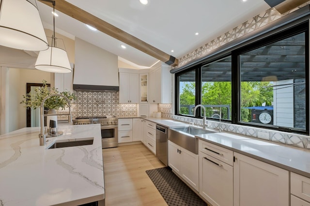kitchen with lofted ceiling with beams, a sink, white cabinetry, and stainless steel appliances