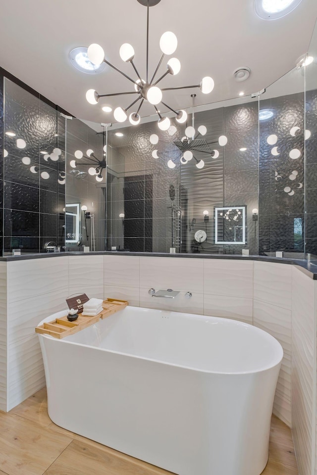 full bathroom featuring wood finished floors, a freestanding bath, tile walls, and a shower stall