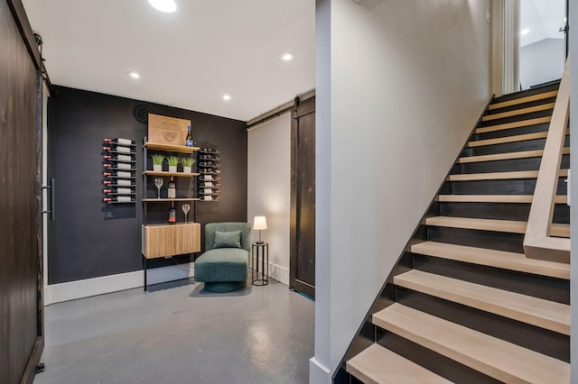 stairs featuring recessed lighting, baseboards, a barn door, and finished concrete flooring