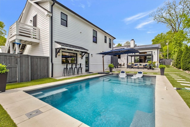 back of house featuring fence, an outdoor hangout area, a fenced in pool, a balcony, and a patio