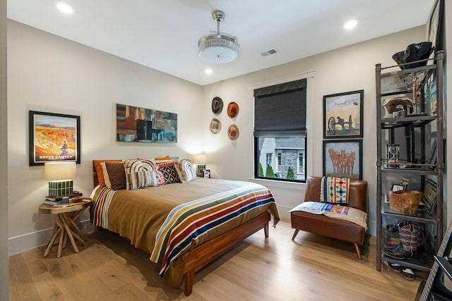 bedroom with baseboards, recessed lighting, wood finished floors, and visible vents