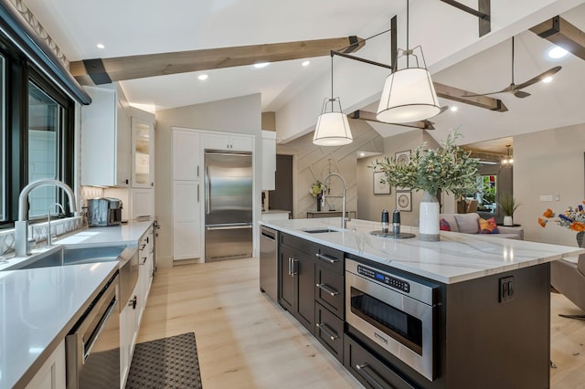 kitchen featuring white cabinetry, a sink, lofted ceiling with beams, built in appliances, and light wood-style flooring