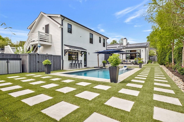 rear view of property with a fenced backyard, a gate, a fenced in pool, and a lawn