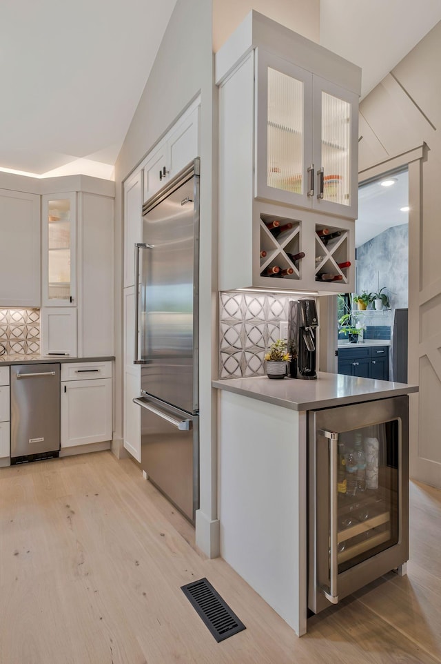 kitchen featuring visible vents, decorative backsplash, wine cooler, white cabinets, and appliances with stainless steel finishes