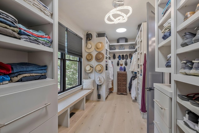 walk in closet with a chandelier and light wood finished floors