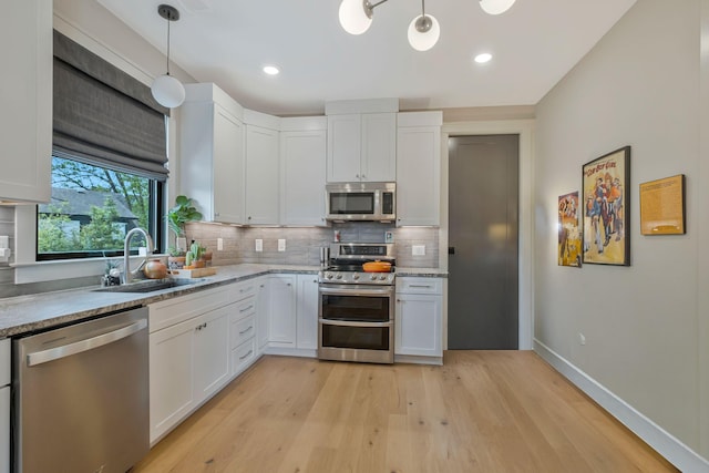 kitchen featuring baseboards, white cabinetry, tasteful backsplash, a sink, and appliances with stainless steel finishes