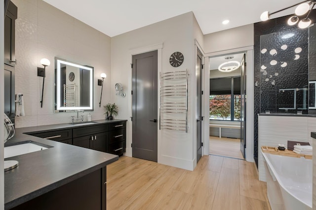 full bathroom with vanity, wood finished floors, tiled shower, and a soaking tub