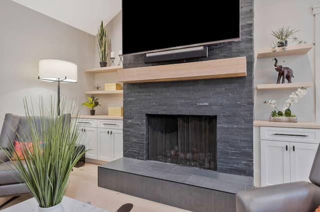 living area with vaulted ceiling, light wood finished floors, and a tile fireplace