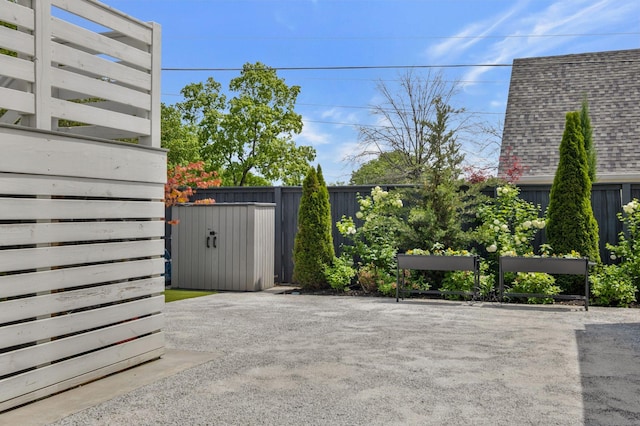 exterior space featuring fence, a shingled roof, a shed, an outbuilding, and a patio