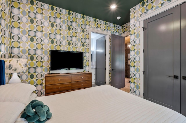 bedroom featuring ensuite bathroom, a closet, and wallpapered walls