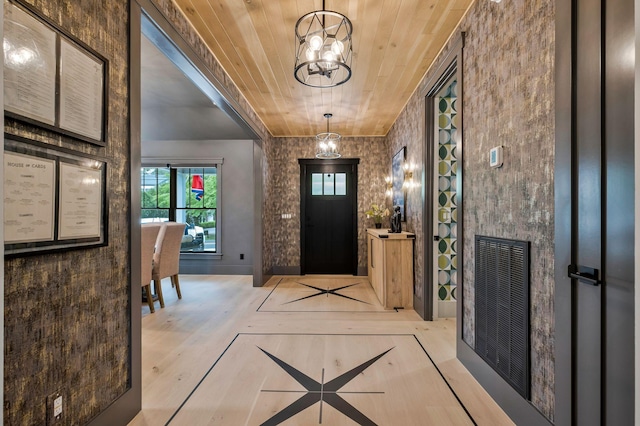foyer entrance with an inviting chandelier, wood ceiling, visible vents, and wood finished floors