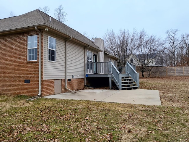 rear view of property with fence, a wooden deck, crawl space, a patio area, and a lawn